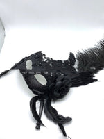 Mascarade vénitienne tenant un masque de plumes demi-visage
